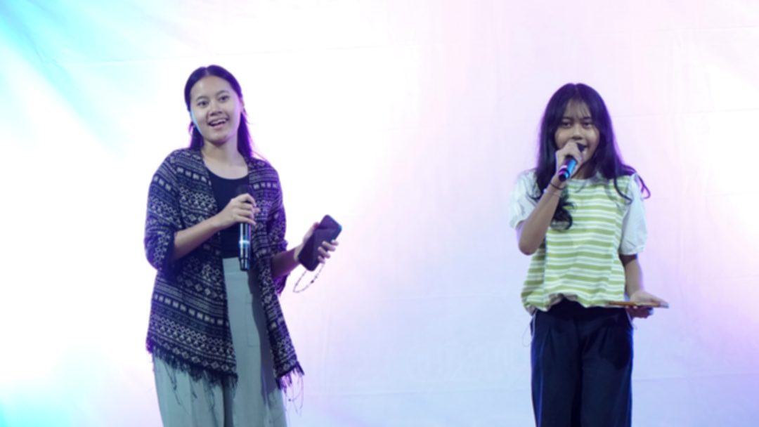 Dua pembawa acara membawakan lagu dengan wireless microphone pada HUT Lingkungan Santo Petrus